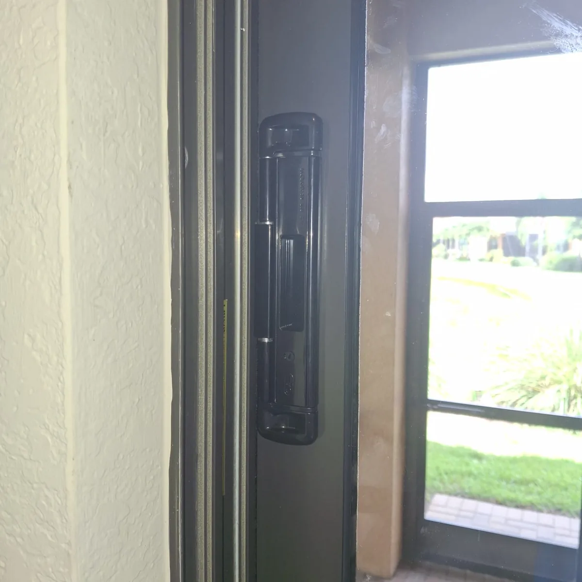 Black sliding glass door lock and handle set fitted to a grey patio slider