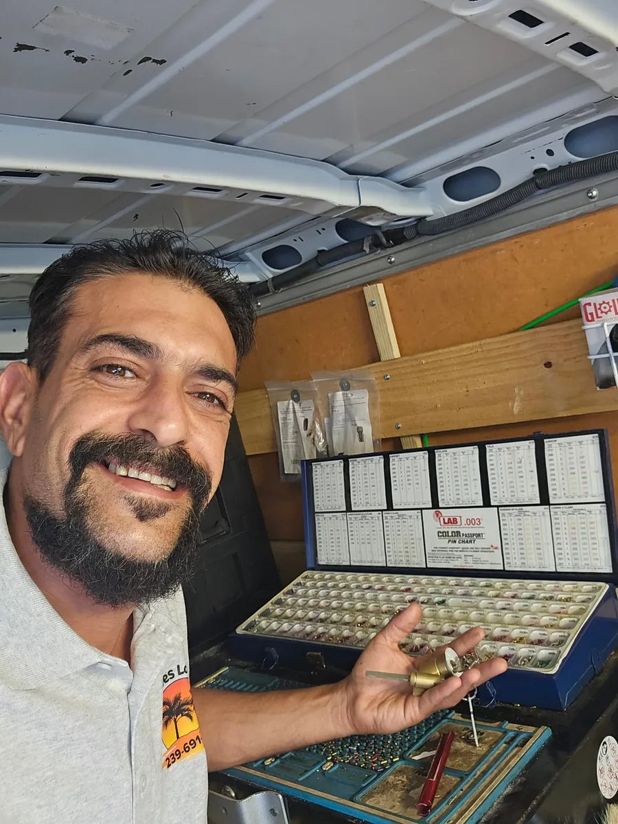 Locksmith holding a brass lock cylinder and key beside a pin kit and pinning tray inside a work van